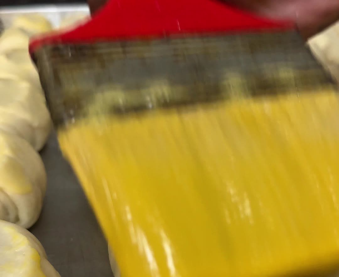Pães sendo pincelados antes de assar